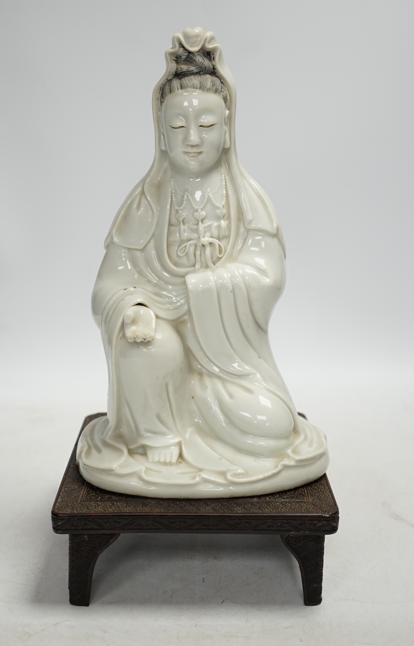 An 18th century Chinese white glazed pottery model of Guanyin on a square hardwood stand, figure 23cm. Condition - poor, hand missing, chips